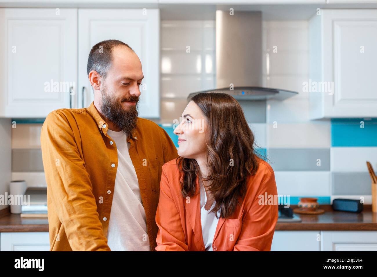 Happy young couple talking at home in kitchen. Family Husband and wife enjoying spending time together while standing in apartment interior. family Stock Photo