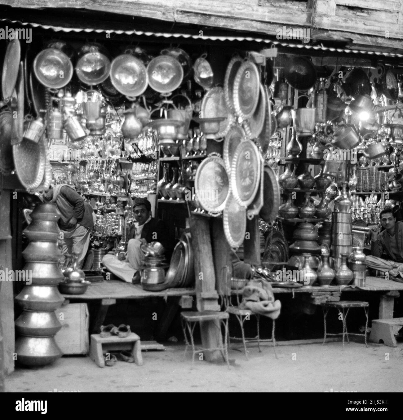 Traders Ironmongers sit inside their shops in Peshawar amongst the pots and pans. Pesthe capital of the North West Frontier province of Pakistan. February 1961 l Stock Photo