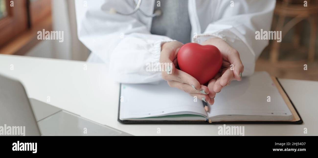 Crop shot of female doctor with stethoscope holding heart model ...