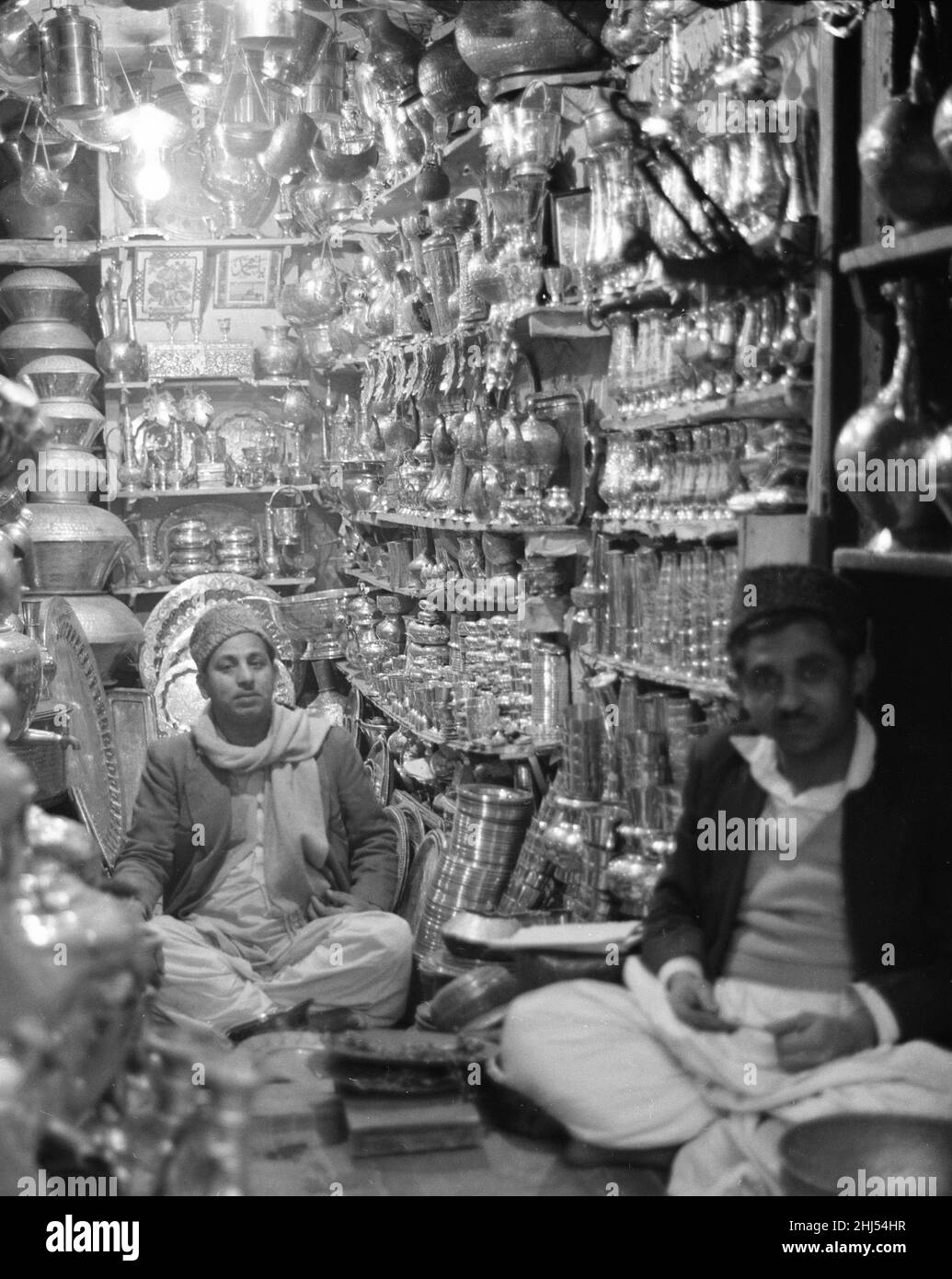 Traders Ironmongers sit inside their shop in Peshawar amongst the pots and pans. Pesthe capital of the North West Frontier province of Pakistan. February 1961  l Stock Photo