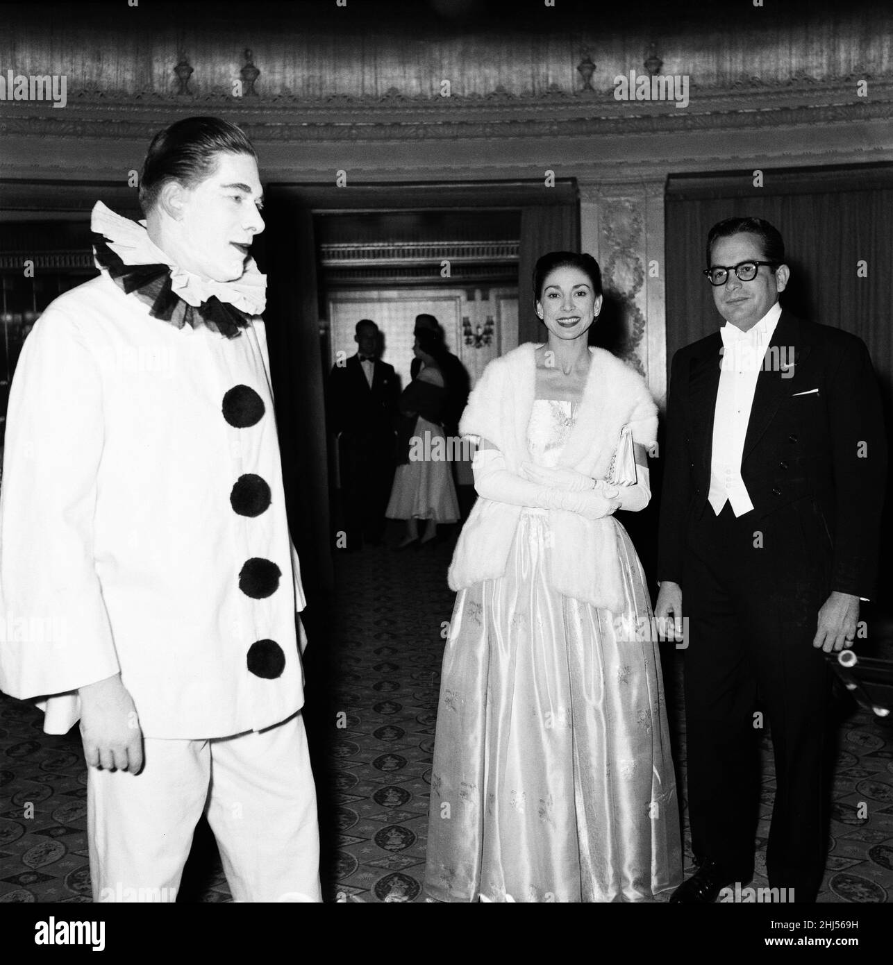 Annual 'Opera Ball' in aid of the English Opera Group is held at The Dorcester Hotel in London 22nd February 1956.   Hundreds of guests connected with opera attended the Opera Ball, many in fancy dress and danced till 3am.     Pictured: George Henry Hubert Lascelles, 7th Earl of Harewood, dressed as a clown, greets Margot Fonteyn as she arrives for the ball Stock Photo