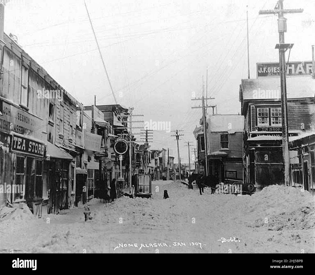 Street covered in snow showing storefronts and powerlines, Nome, Alaska