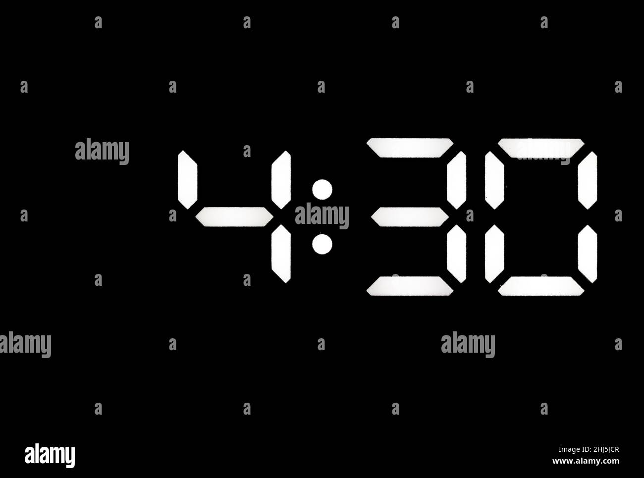 Real white led digital clock on a black background showing time 4:30 Stock Photo
