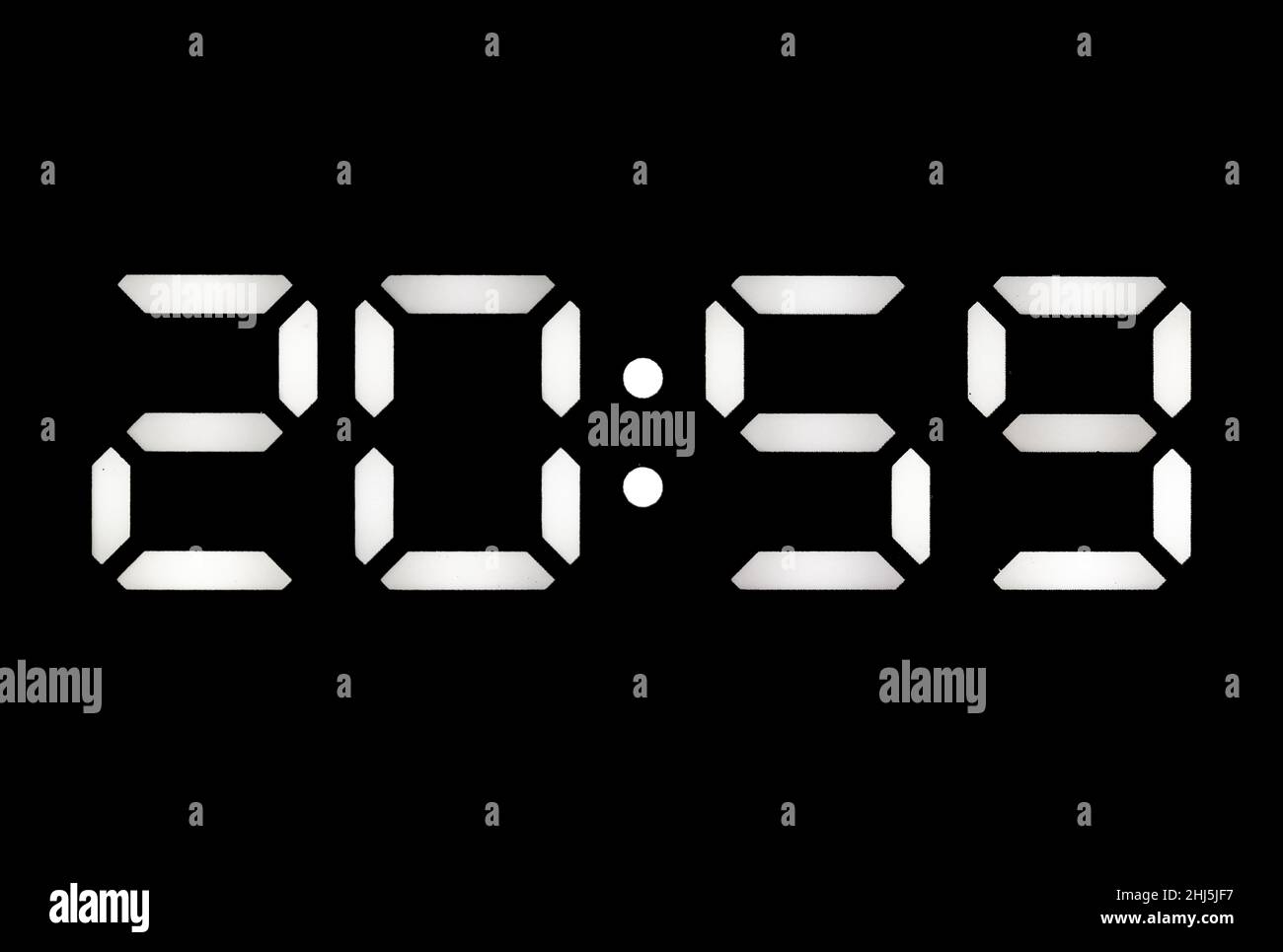 Real white led digital clock on a black background showing time 20:59 Stock Photo