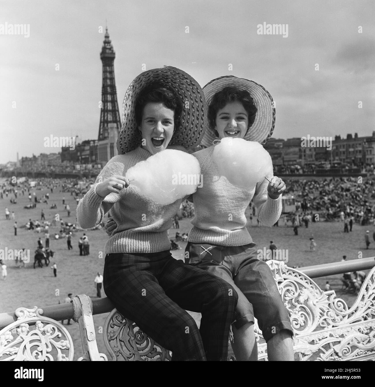 Jean Clark and Mary Cuppler enjoy eating candy floss on the pier at Blackpool, Lancashire. 18th July 1957. Stock Photo