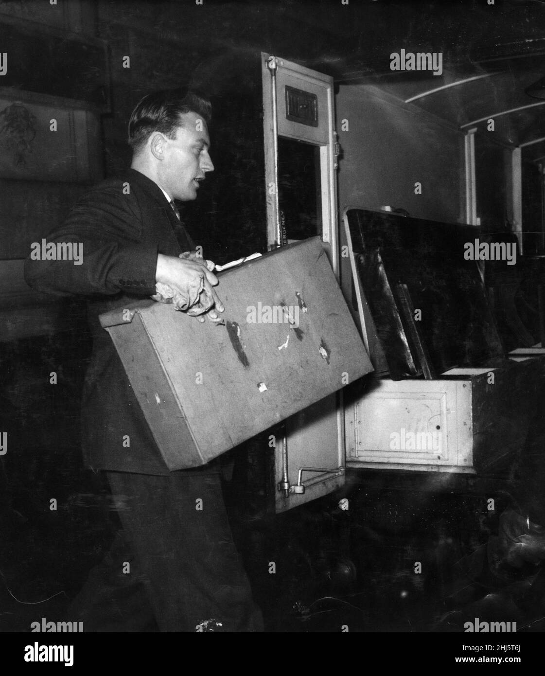 The Five Pound Note Forgery Crime of 1957. Picture shows a policeman with a suitcase full of the forged five pound notes used as evidence at The Old Bailey.  Mr George Morgan, 37, a car dealer of Baskerville Road, Wandsworth was found guilty of conspiracy to forge five pound notes and of possessing 540 forged notes.  He was jailed for eight years in January 1958. The first man to be tried for the crime was Albert Small who was jailed in December 1957.   A total of 5 people was tried at The Old Bailey in connection with the forging and printing of five pound notes and circulating them.  Picture Stock Photo