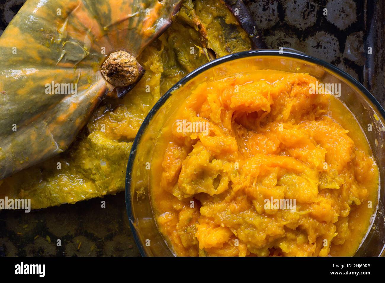 Pumpkin puree in glass bowl and peel of baked pumpkin on baking tray Stock Photo