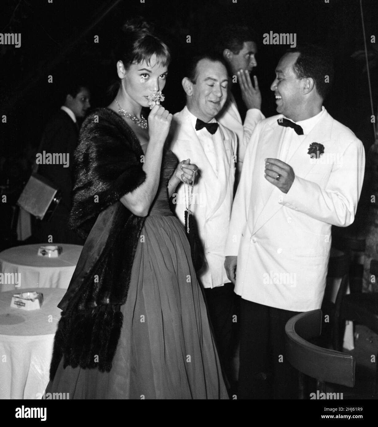 1956 Venice Film Festival, Friday 31st August 1956. Our Picture Shows ... Italian actress Elsa Martinelli smelling flower, in background, Bernard McElwaine Sunday Pictorial Journalist. Stock Photo