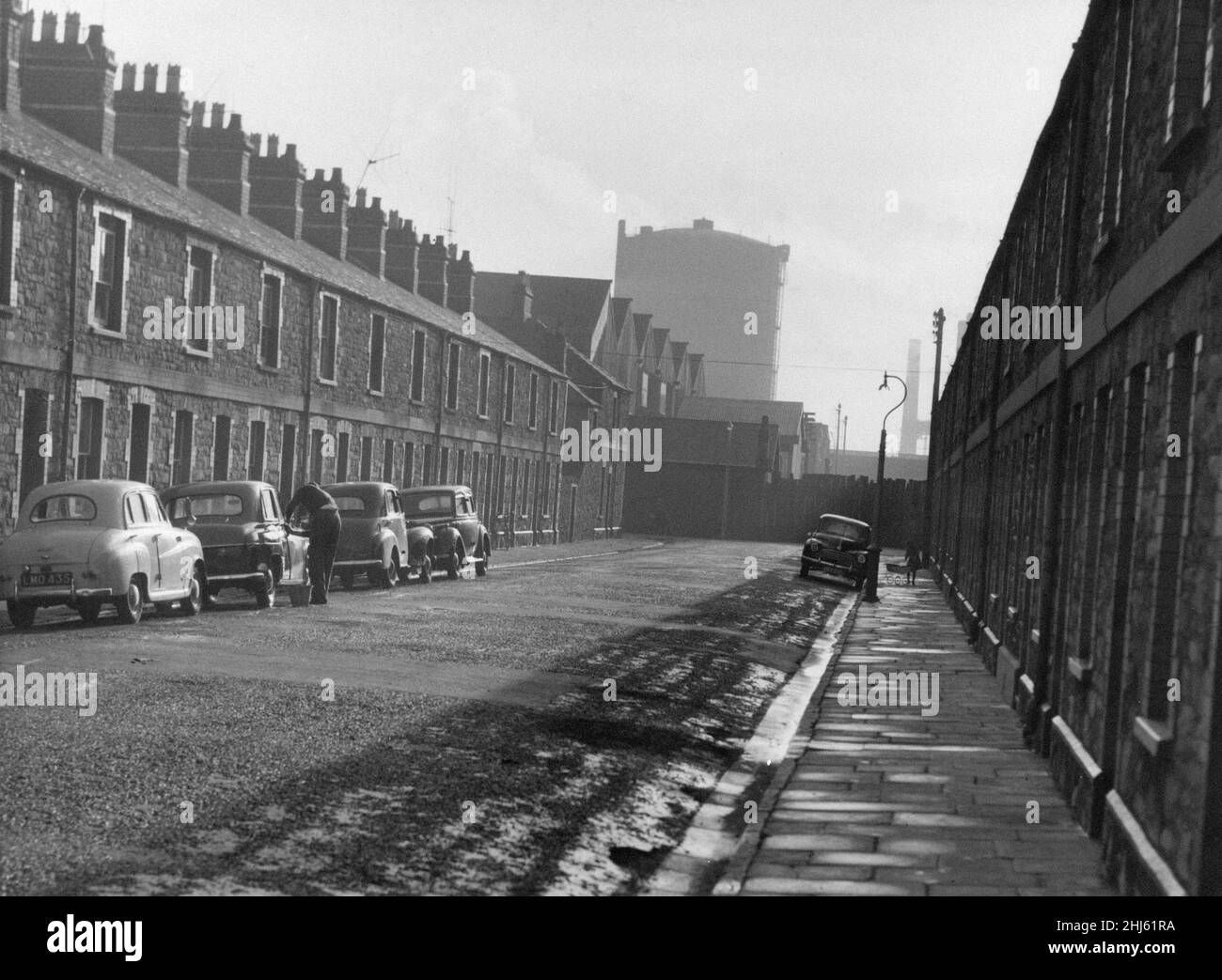Kilcattan Street in Adamsdown, an inner city area and community in the south of Cardiff, Wales. 23rd January 1961. Our Picture Shows, Kilcattan Street overshadowed by the giant gasometer of the Dowlias works, and the noise of the screaming saws from the timber works. Stock Photo
