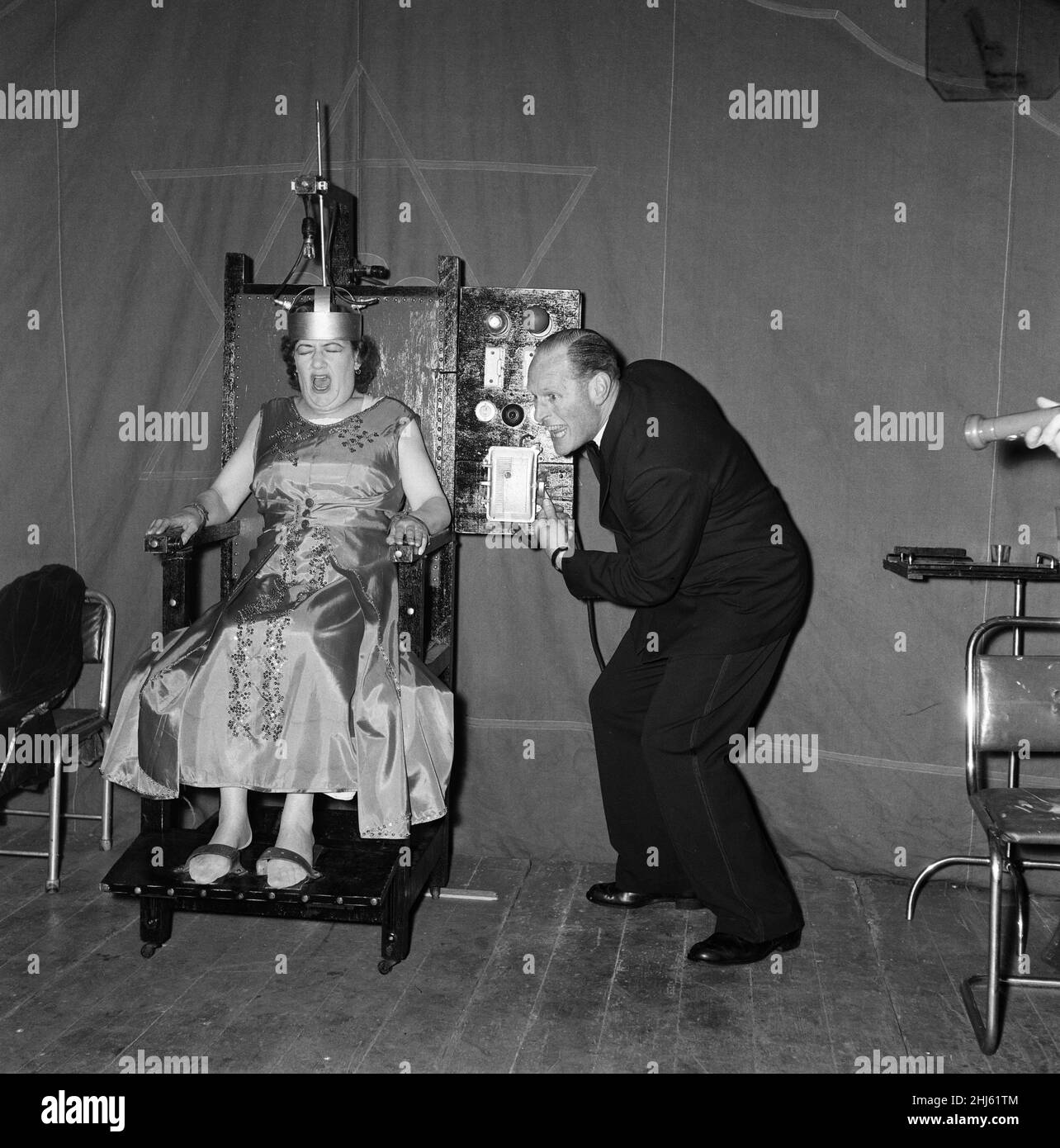 A man electrocuting his wife for a fairground sideshow. Boston, Lincolnshire. 10th May 1957. Stock Photo