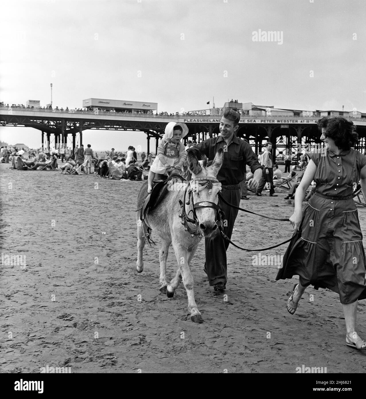 A young holiday makers having a Donkey ride on the beach at Blackpool, Lancashire. 18th July 1957. Stock Photo