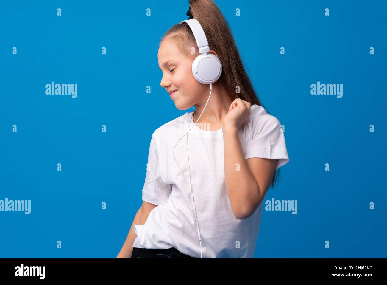 Little girl child wear headphones listen to music over blue background