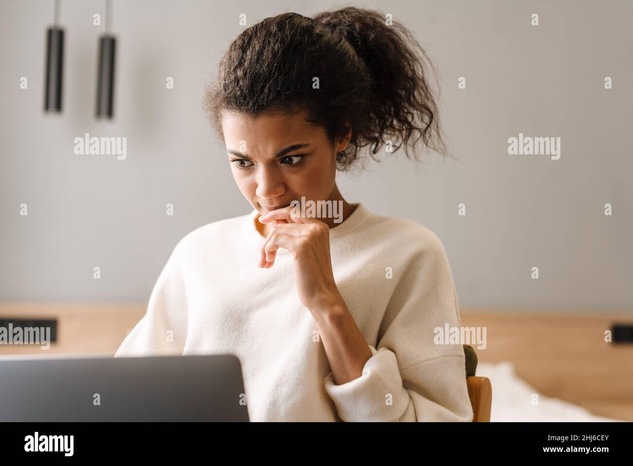 Smiling young african woman using laptop computer while sitting on a ...