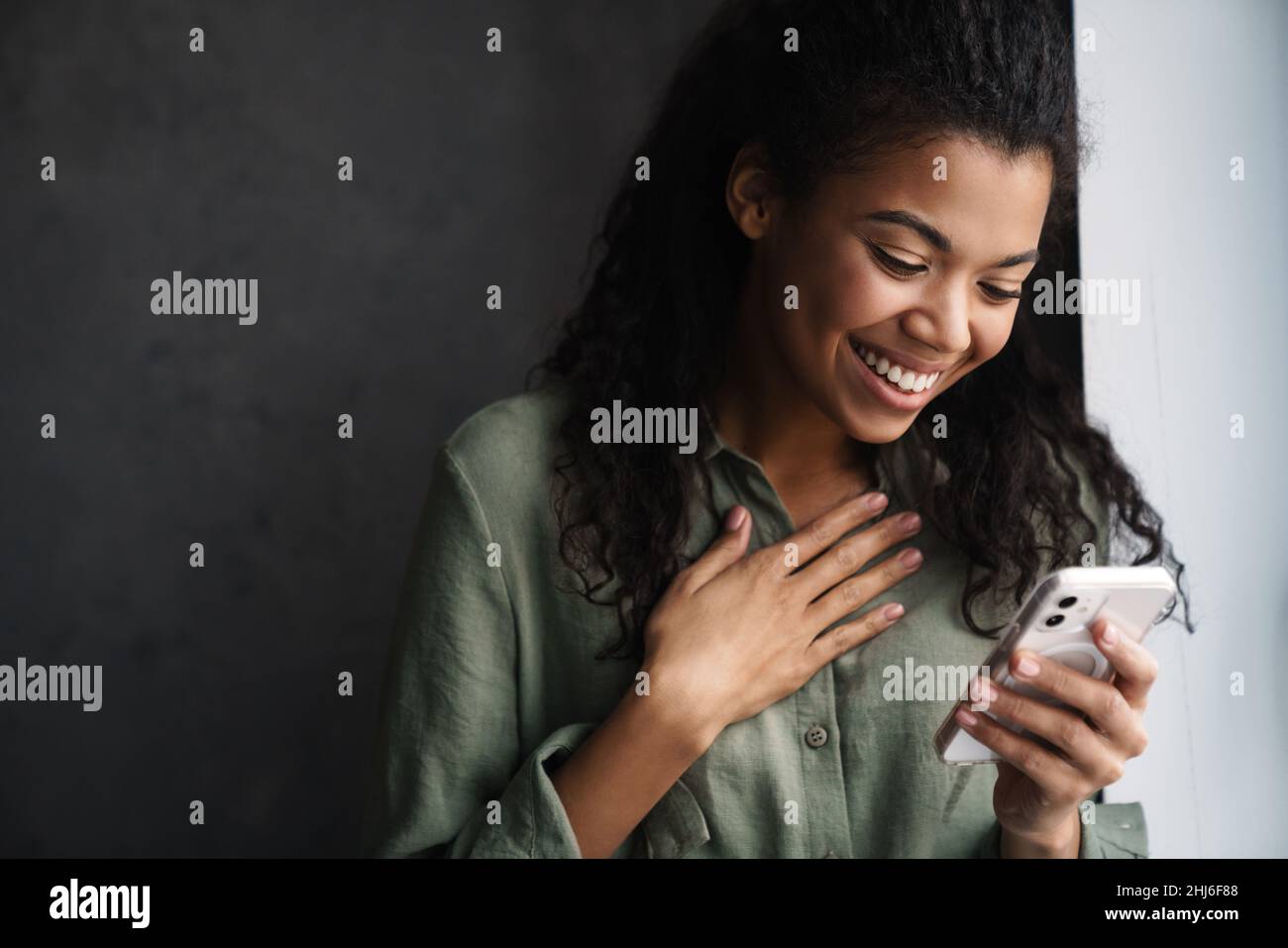 Black young woman laughing while using mobile phone indoors Stock Photo ...