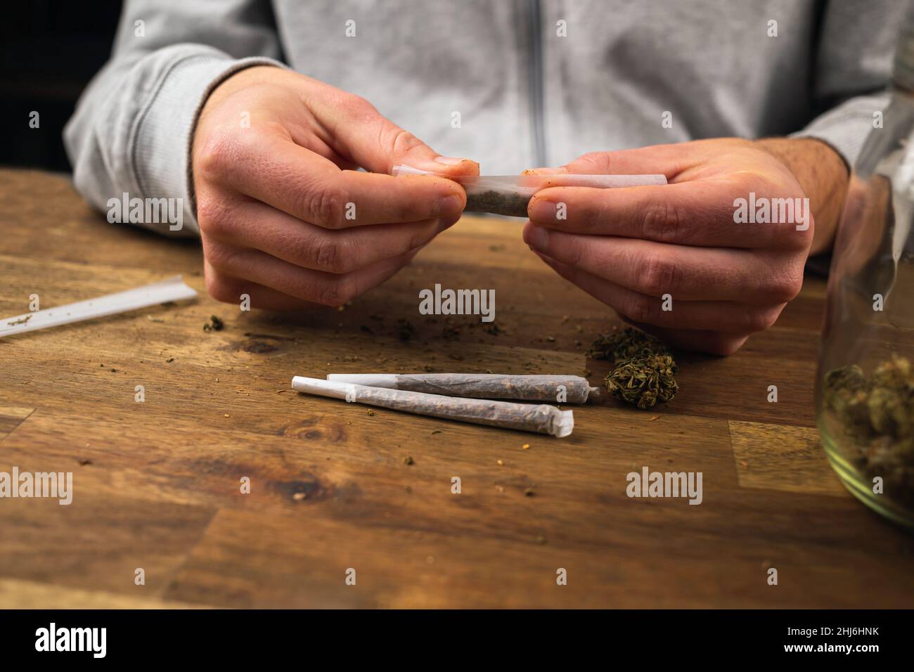 Man rolling marijuana cannabis joint in coffee shop Amsterdam with CBD weed  buds in glass jars Stock Photo - Alamy