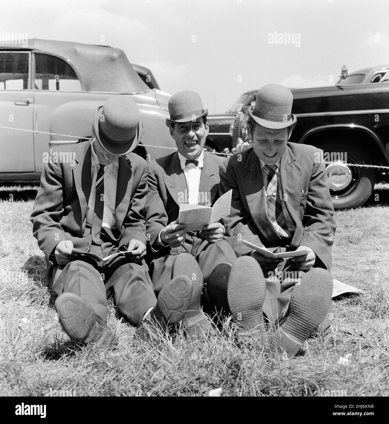 Derby Day at Epsom. Pictured, three lads from Newmarket sitting on the grass studying form. All wearing hats they describe as 'hard hitters' they are similar to bowlers but have a curved brim. 3rd June 1959. Stock Photo