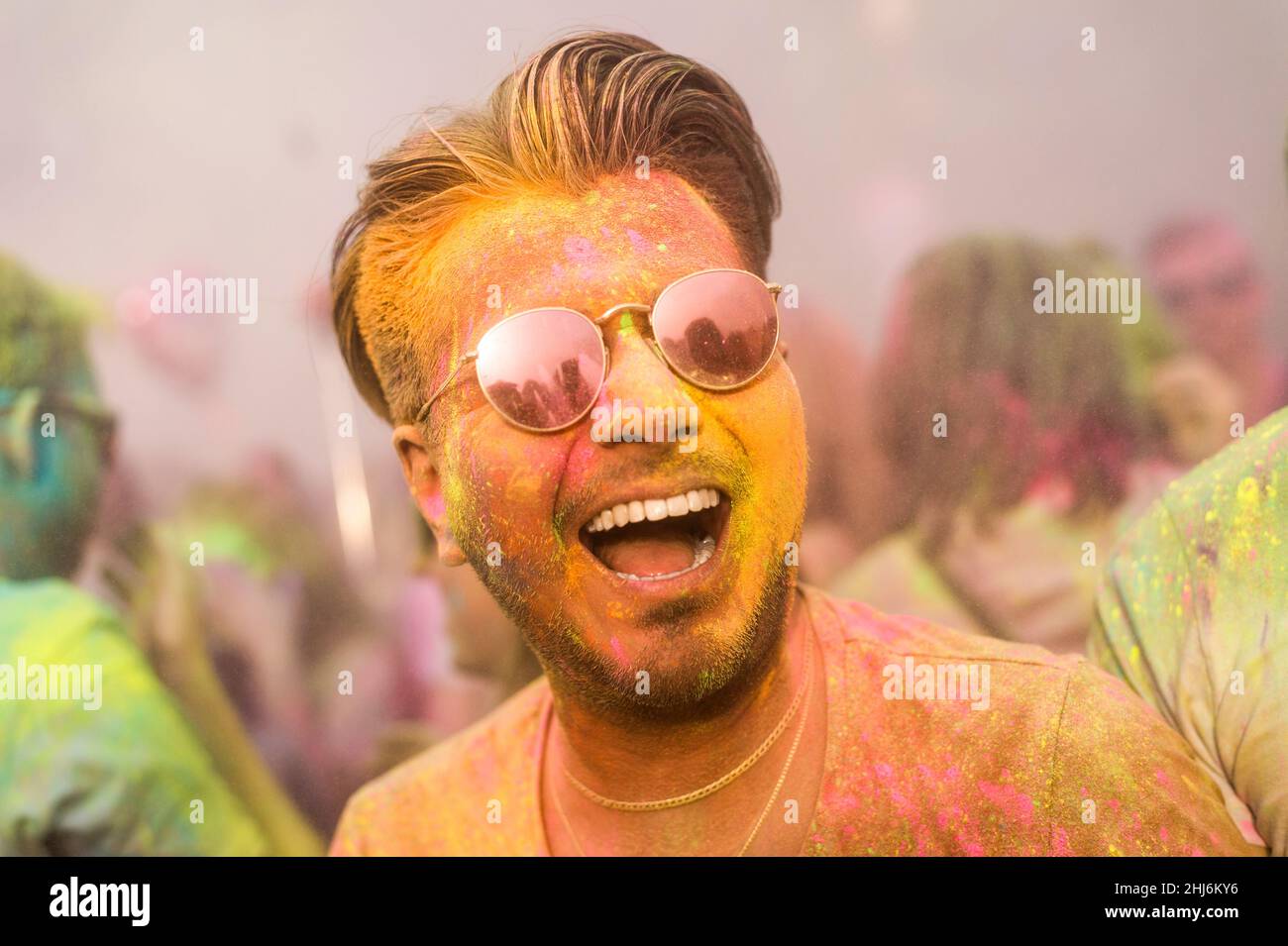 handsome smiling black hair man with colorful face having fun on Holi