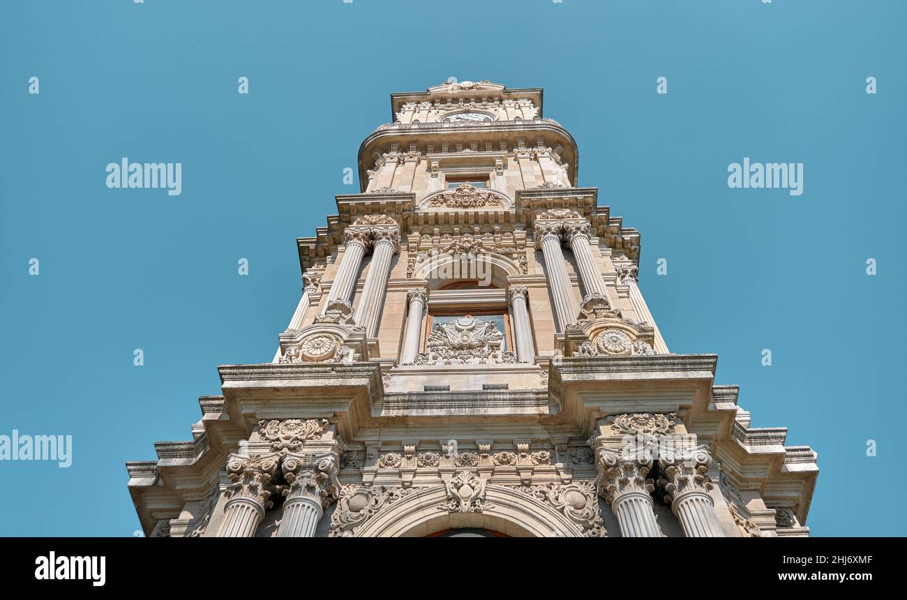 Low angle photo. Low angle photo of Dolmabahce clock tower and blue sky background. Piece of arts of Ottoman architecture, baroque style Stock Photo