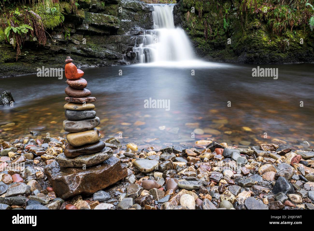 Balanced stone stack with beautiful waterfall background. Stacked rocks balancing art. Environment, ecosystem impact concept. Brecon Beacons, Wales, UK Stock Photo