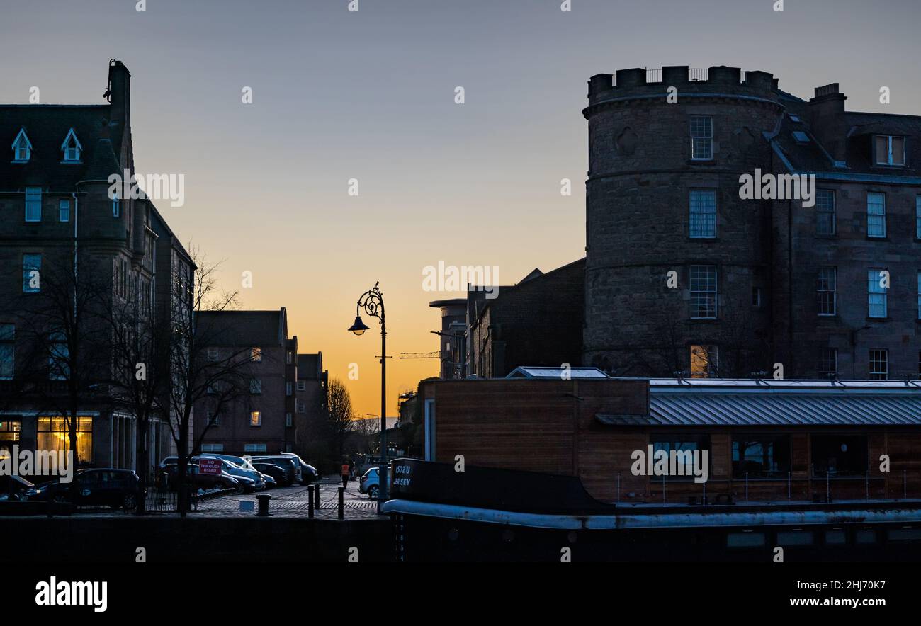 Leith, Edinburgh, Scotland, UK, 27th January 2022. UK Weather: orange dawn sunrise over the historic buildings on The Shore in Leith with a houseboat moored on the riverside of the Water of Leith Stock Photo