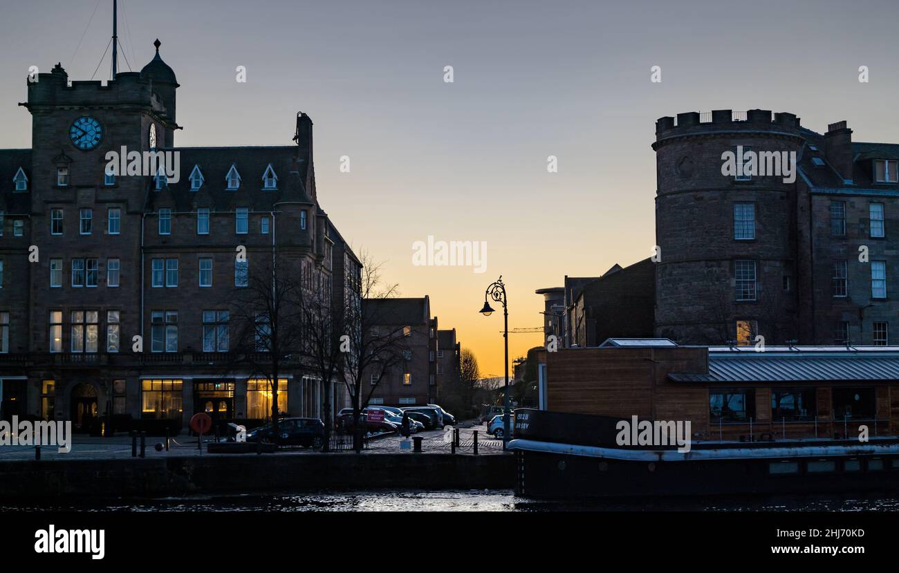 Leith, Edinburgh, Scotland, UK, 27th January 2022. UK Weather: orange dawn sunrise over the historic buildings on The Shore in Leith with a houseboat moored on the riverside of the Water of Leith Stock Photo