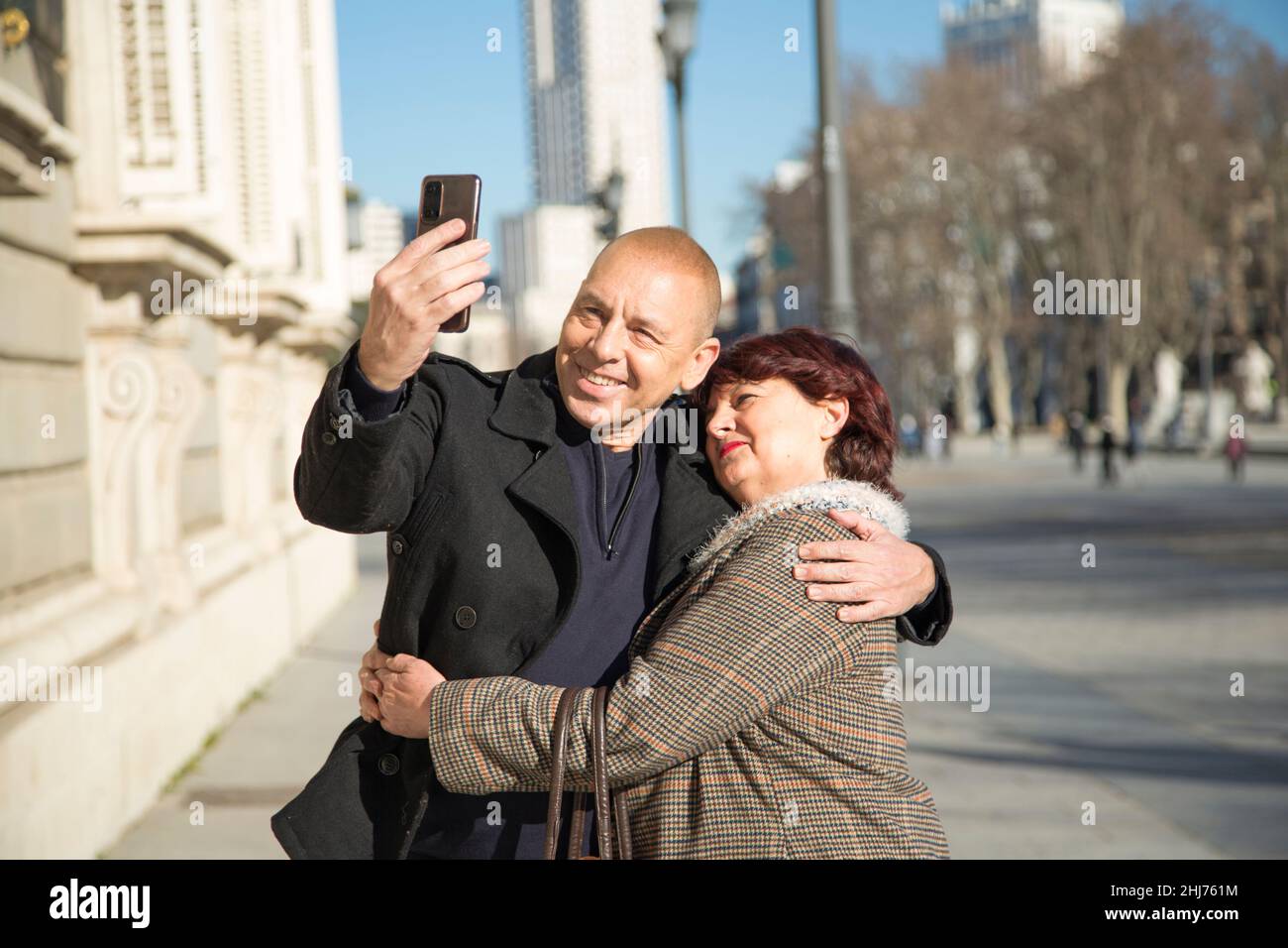 senior Caucasian couple taking a photo with a mobile phone in the street Stock Photo