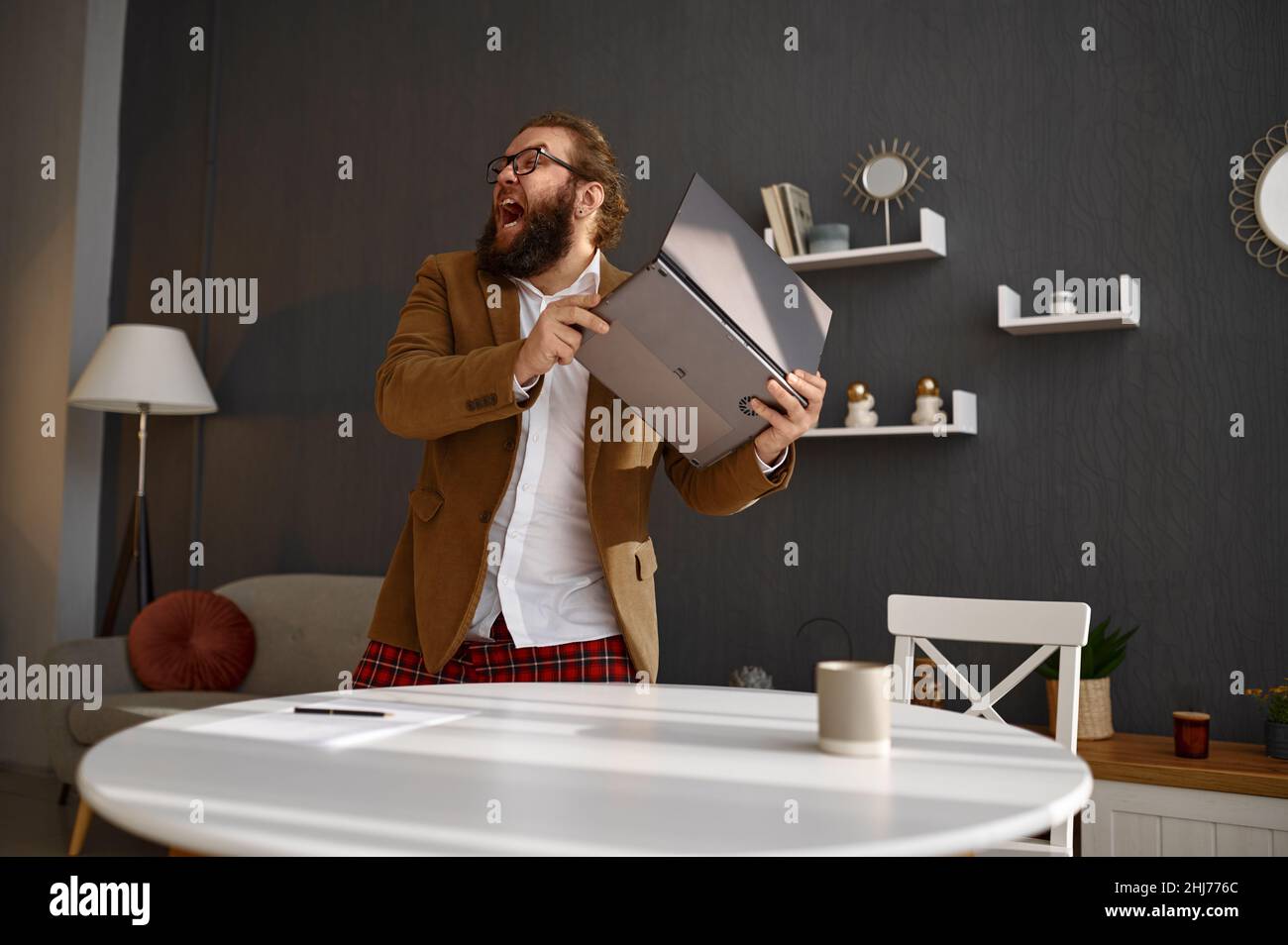 Mad guy in jacket throwing away his laptop Stock Photo Alamy