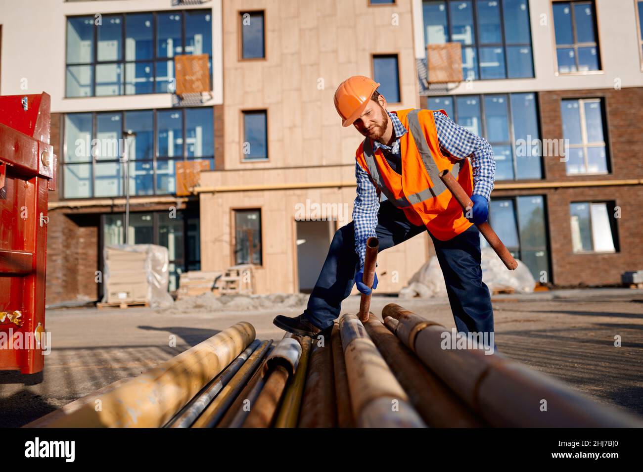 Construction worker holding pipe on site outdoors Stock Photo