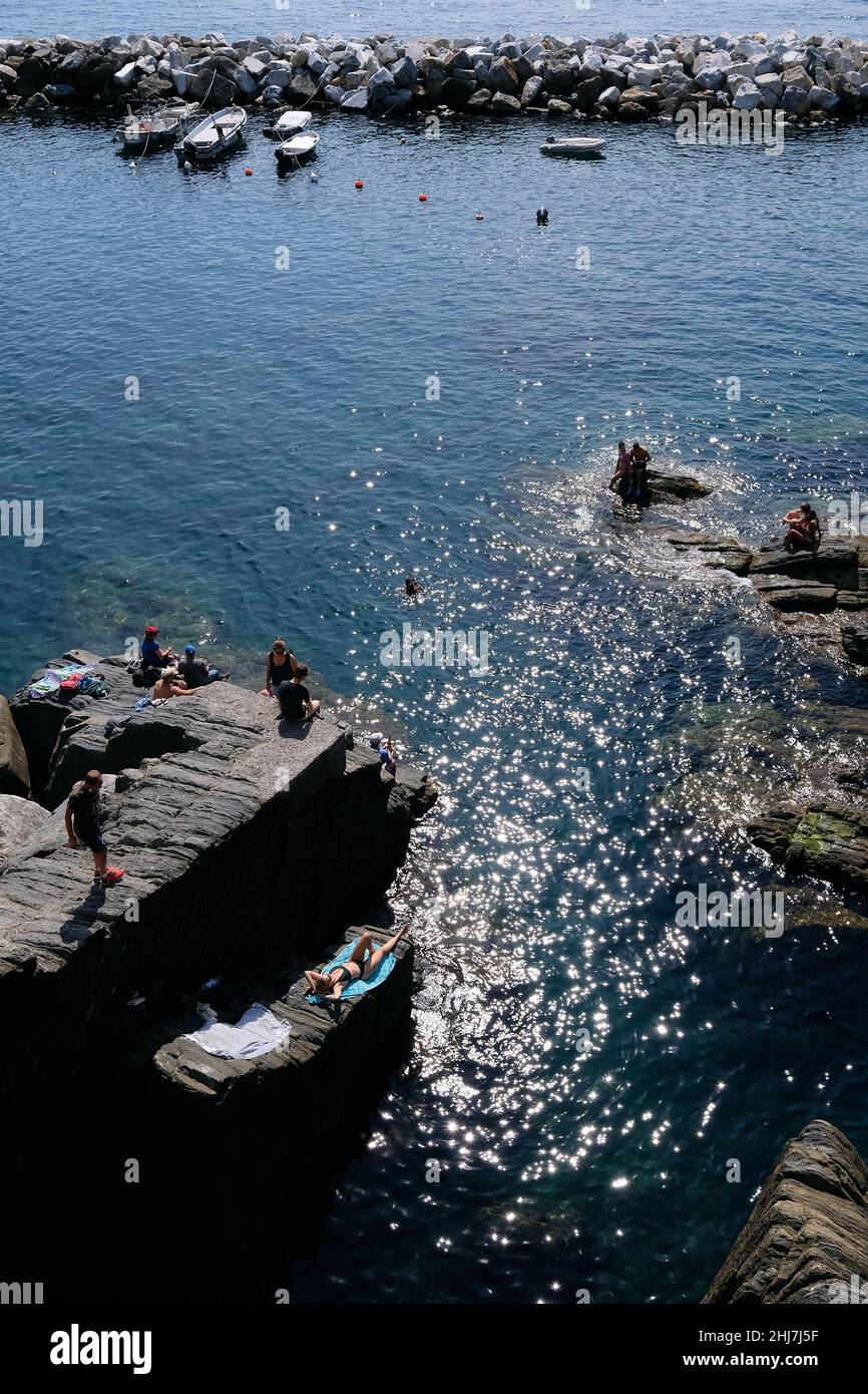Bathers in the easternmost village of Cinque Terre Riomaggiore on the Italian Riviera. Stock Photo