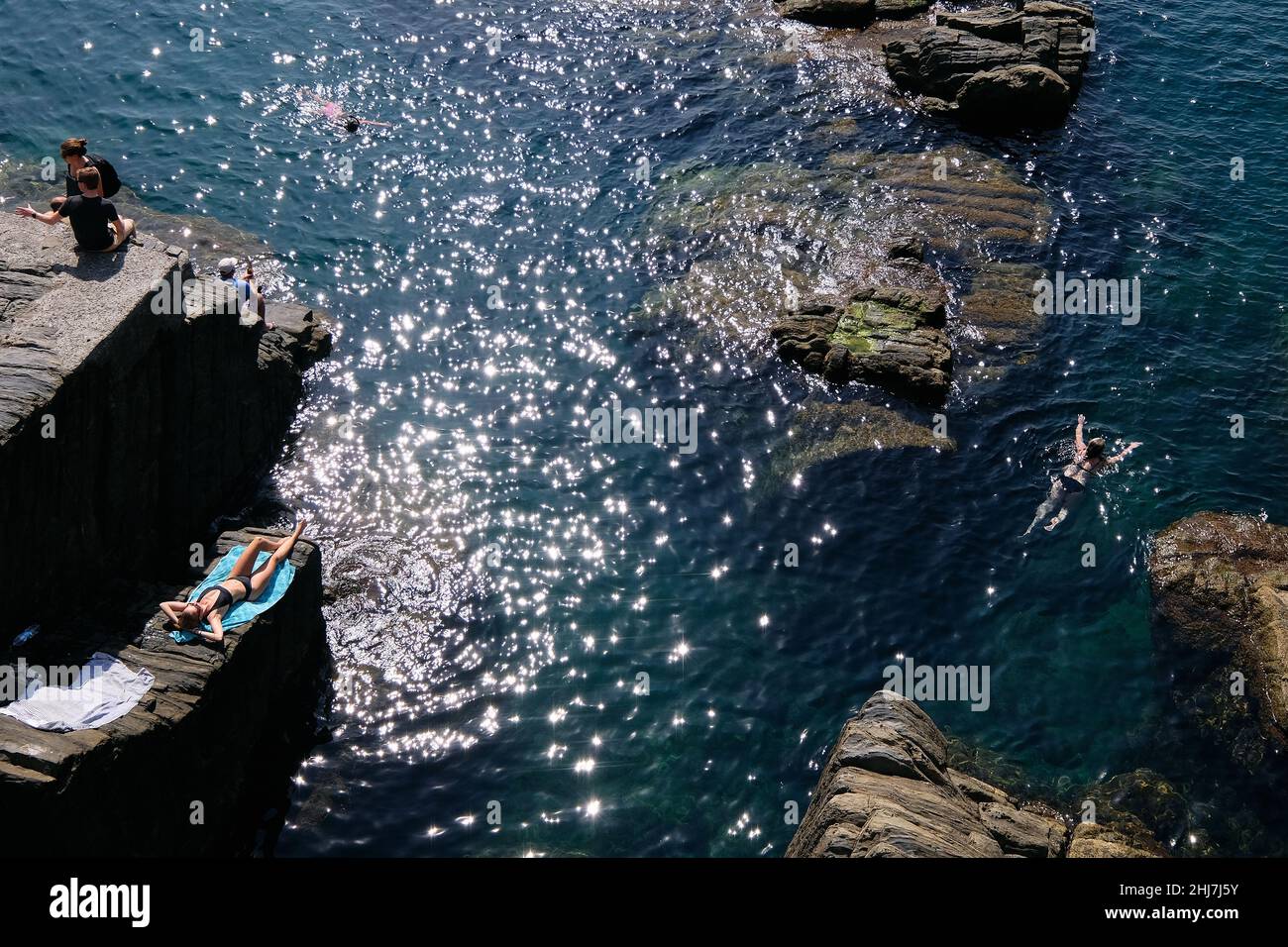 Bathers in the easternmost village of Cinque Terre Riomaggiore on the Italian Riviera. Stock Photo