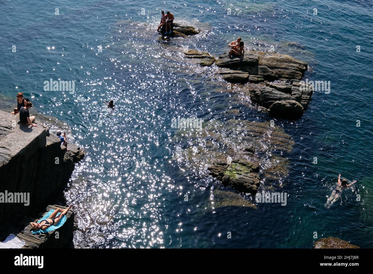 Bathers in the easternmost village of Cinque Terre Riomaggiore on the Italian Riviera. Stock Photo