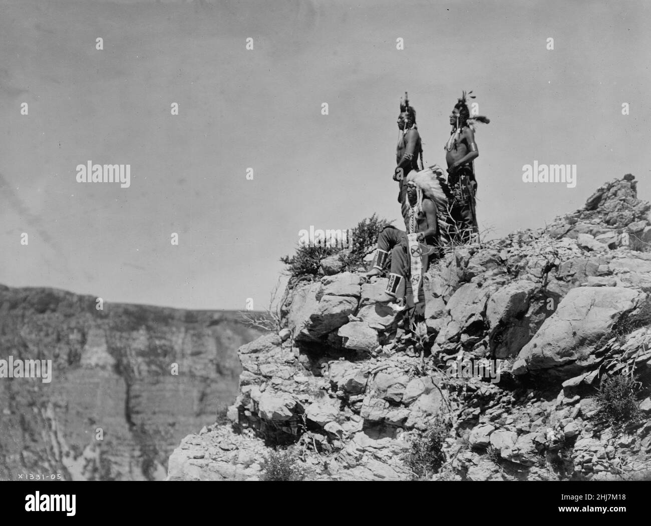 Three Crow Indians, one sitting, two standing, facing left - Curtis, Edward S., photographer. Native american / Indian / American Indian. c 1905. Stock Photo