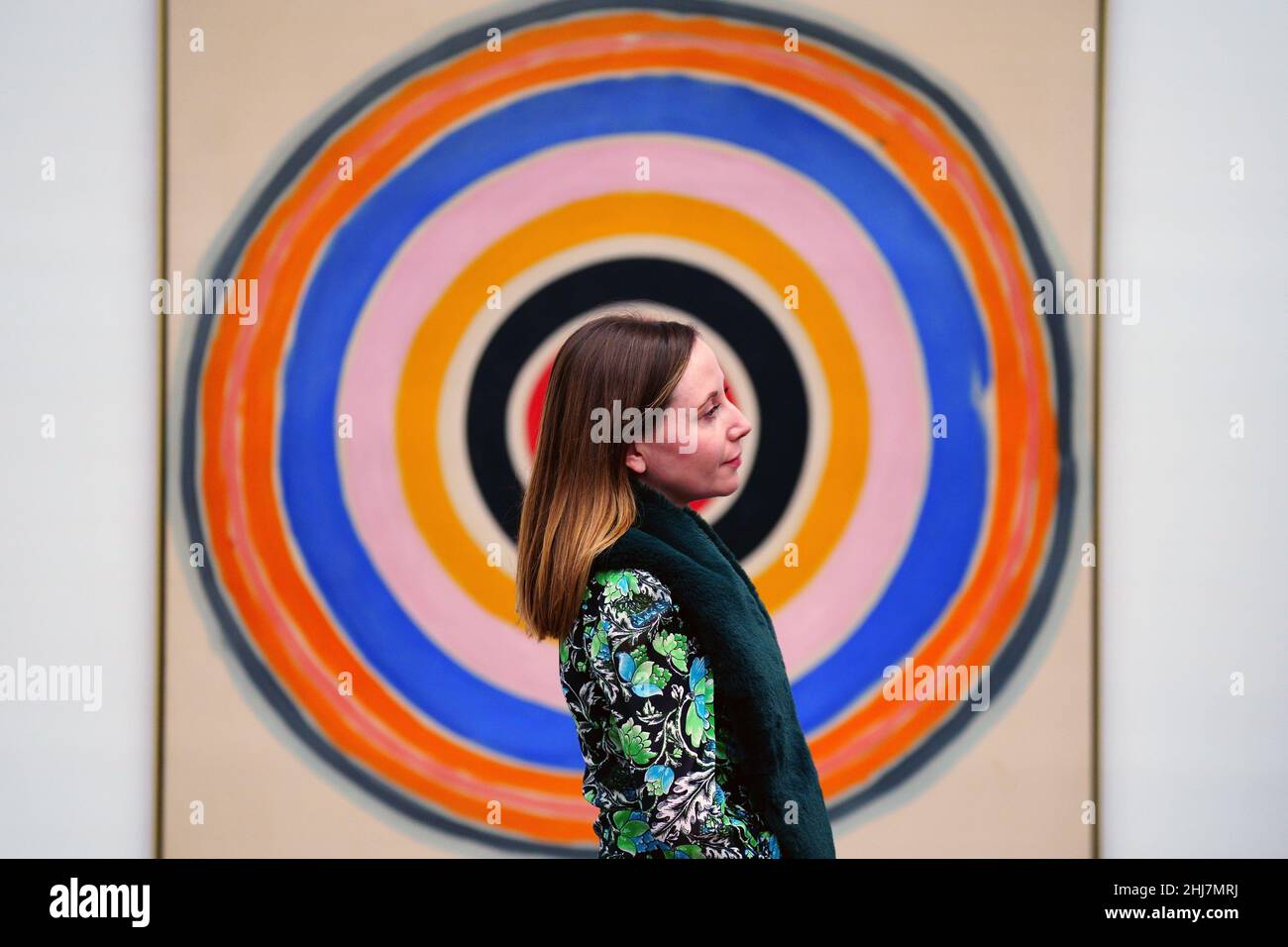 A gallery assistant poses with Turn, 1977, by Kenneth Noland, during a photocall for Caro and North American Painters, an exhibition of sculptures by Anthony Caro from the 1960s and 1970s, shown together with contemporaneous paintings by his friends and peers, at Gagosian in London. Picture date: Thursday January 27, 2022. Stock Photo