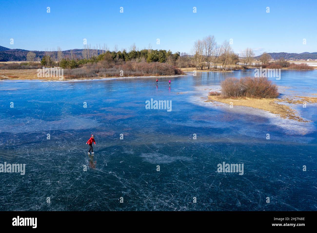 Aerial view of a woman ice skating on frozen intermittent lake Cerknica, Slovenia on a sunny day Stock Photo