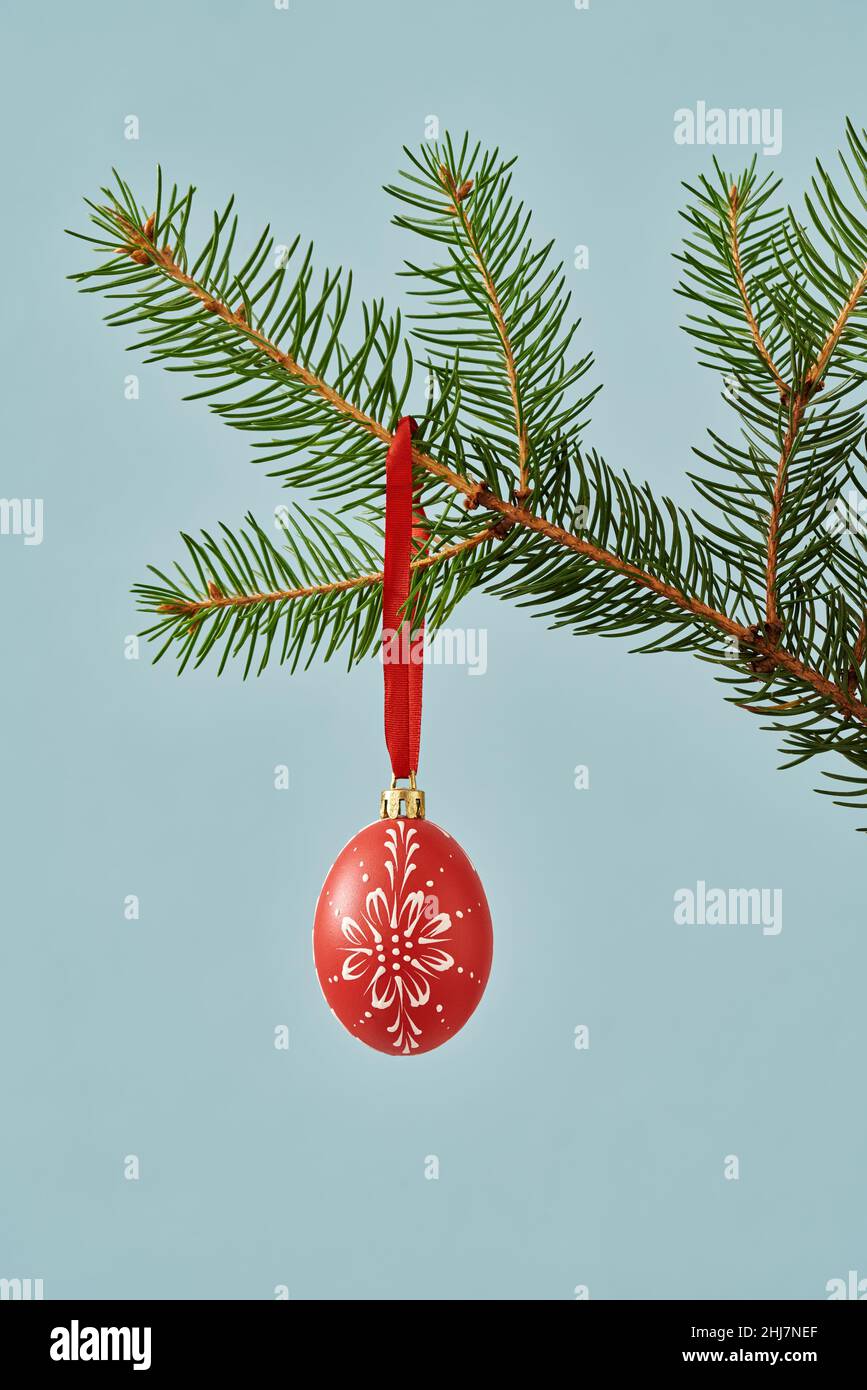 Decorated Easter egg hanging from a Christmas tree branch - concept of ending winter holidays and approaching spring Stock Photo