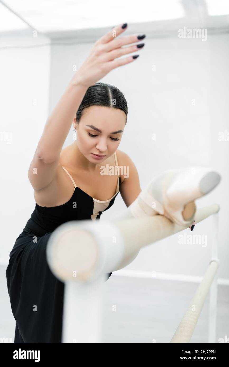young ballerina stretching at barre in studio on blurred foreground Stock Photo