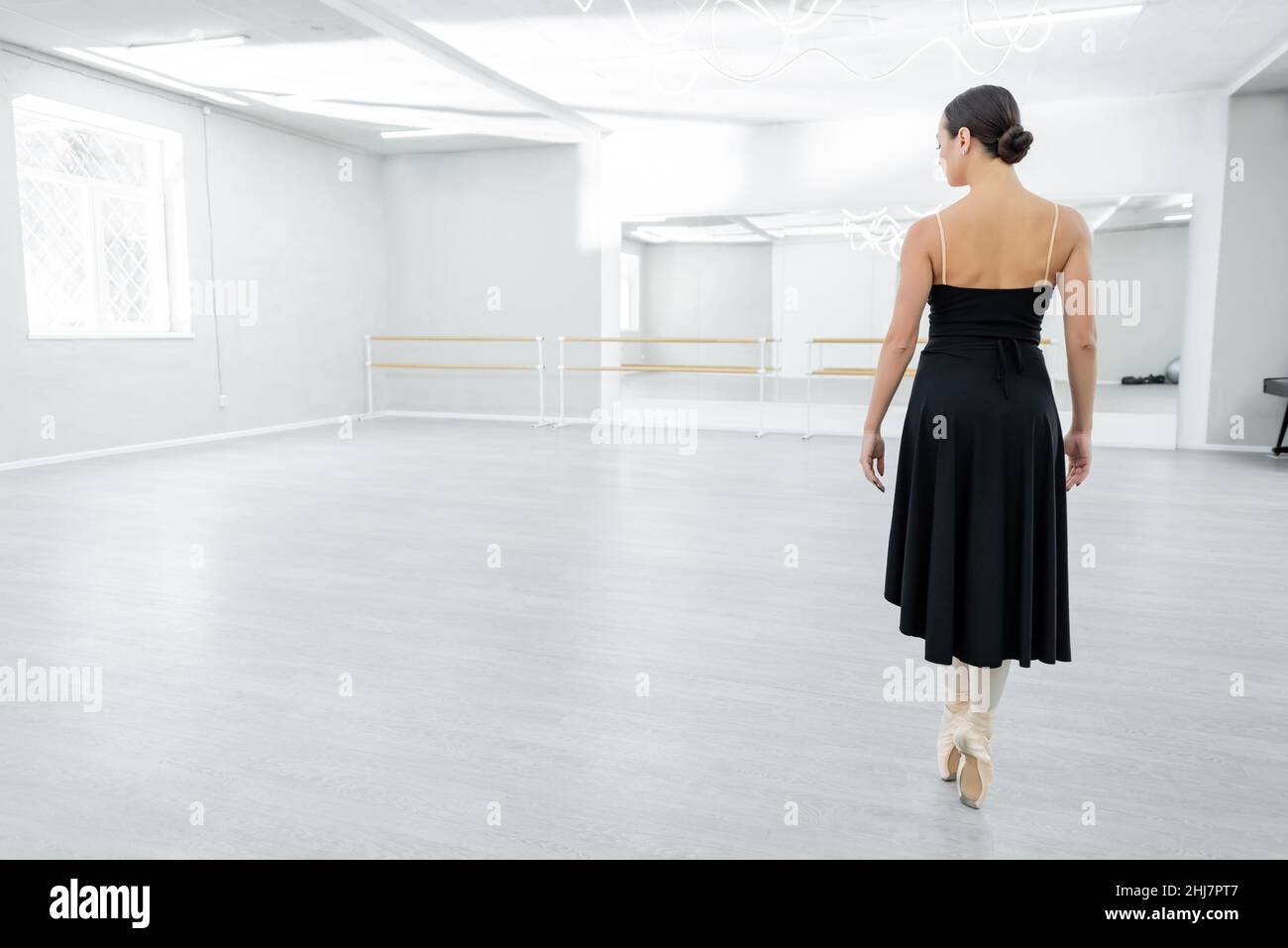 back view of ballerina in pointe shoes standing on toes during