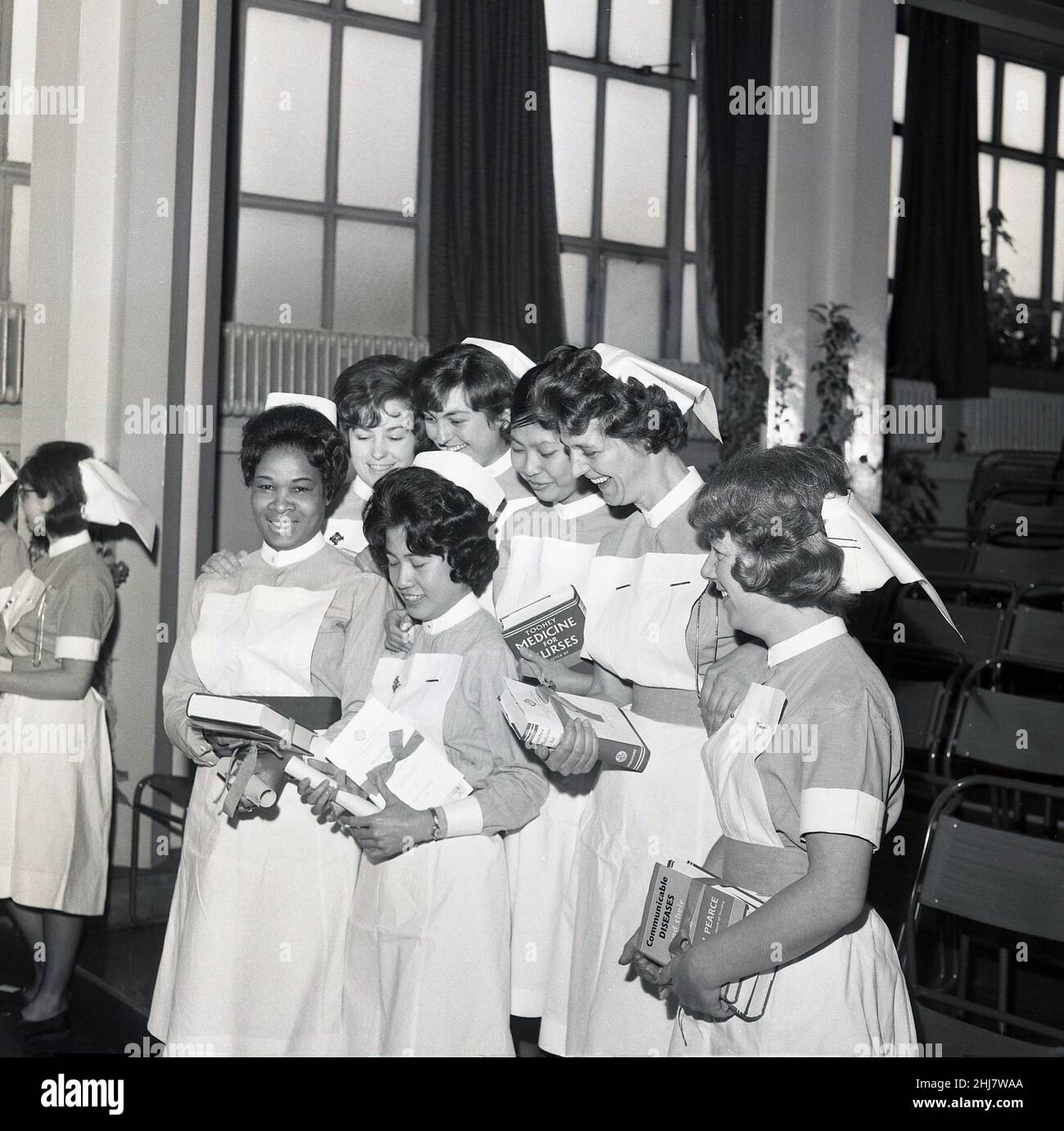 1960s, historical, inside a hall, a group of excited newly qualified female nurses, some holding their scrolls and medical books, Lewisham, Southeast London, England, UK. Several are holding, Medicine for Nurses by M. Toohey, a classic medical book of the 1950s and 60s, which was still be printed in the 1990s. Stock Photo