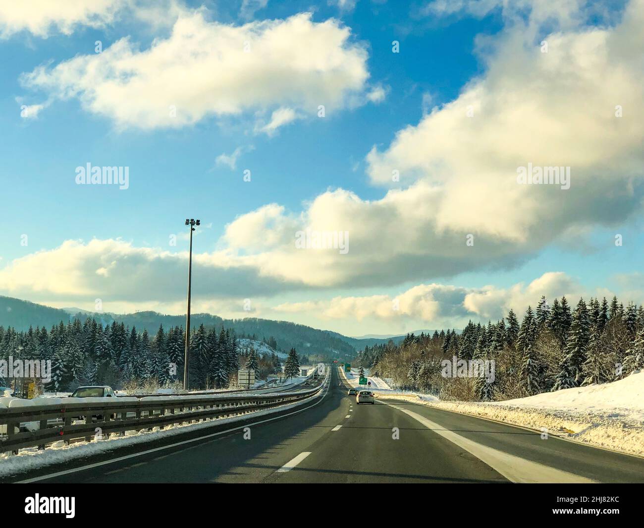 View of a road and a forest in winter Stock Photo - Alamy
