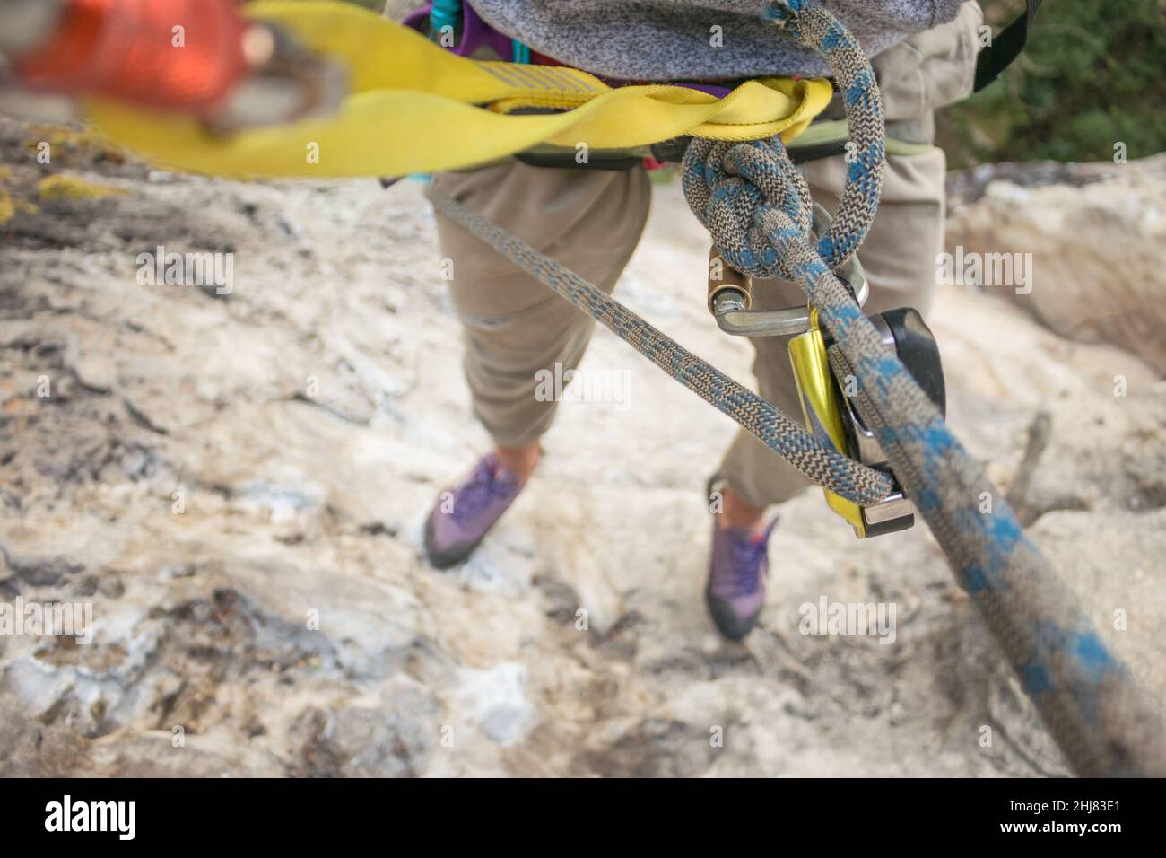 POV: rock climber hangs from rope and gear high above the ground Stock Photo