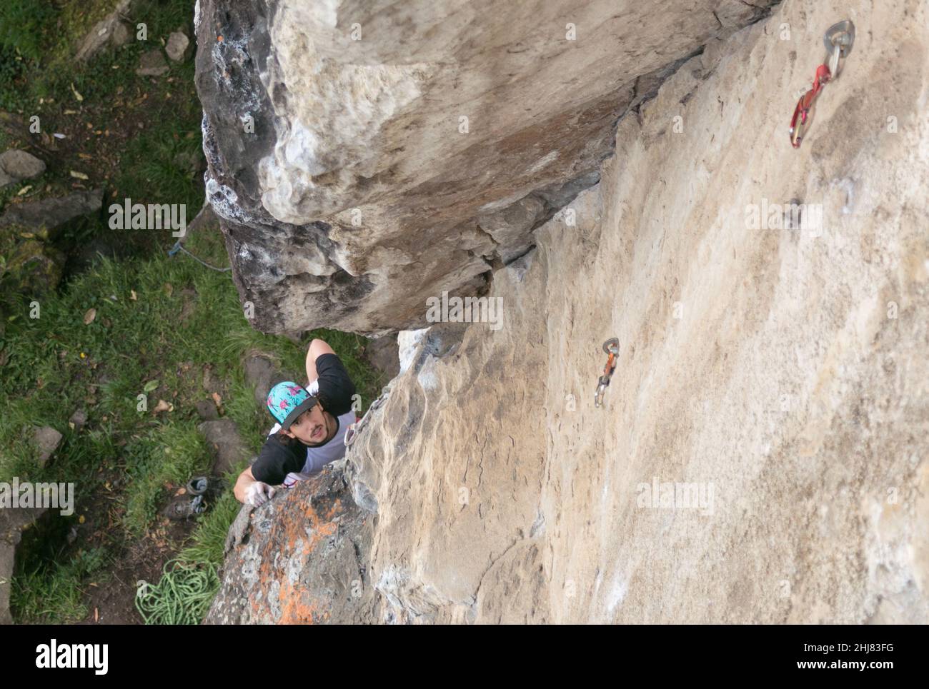 Hispanic rock climber peaking up to see gorgeous textured cliff Stock Photo