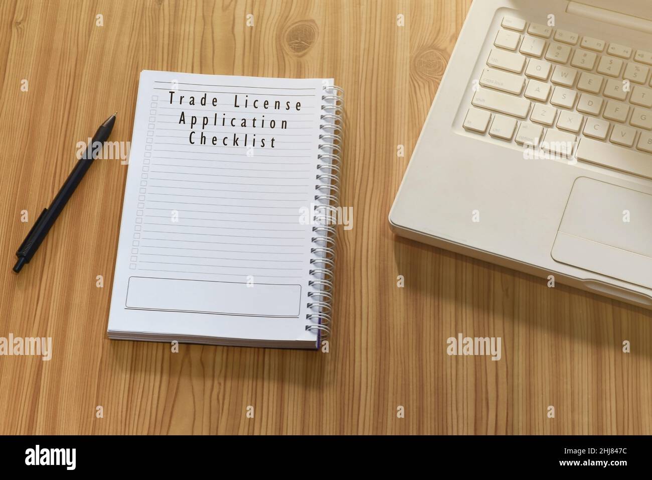 Text on notepad with laptop and pen on wooden desk - Trade license ...