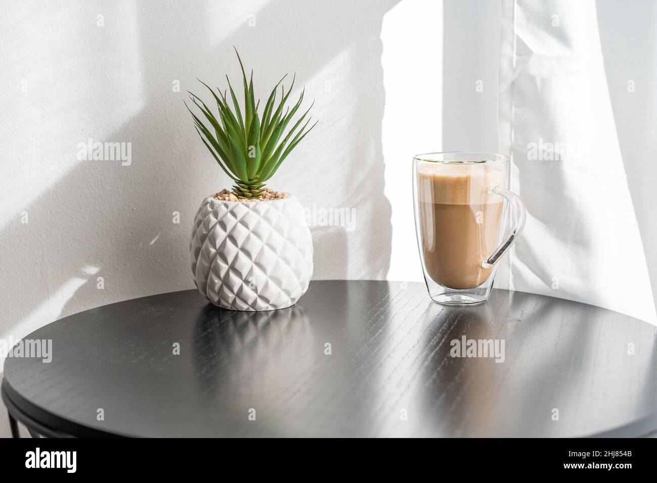 Cup of hot coffee with milk on table. Glass of latte coffee on the table nearly window. Stock Photo