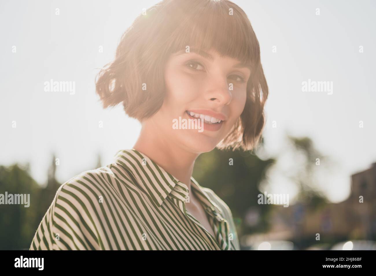 Photo of cute positive cheerful pretty dream lady look camera enjoy sunny day wear striped shirt urban city outside Stock Photo