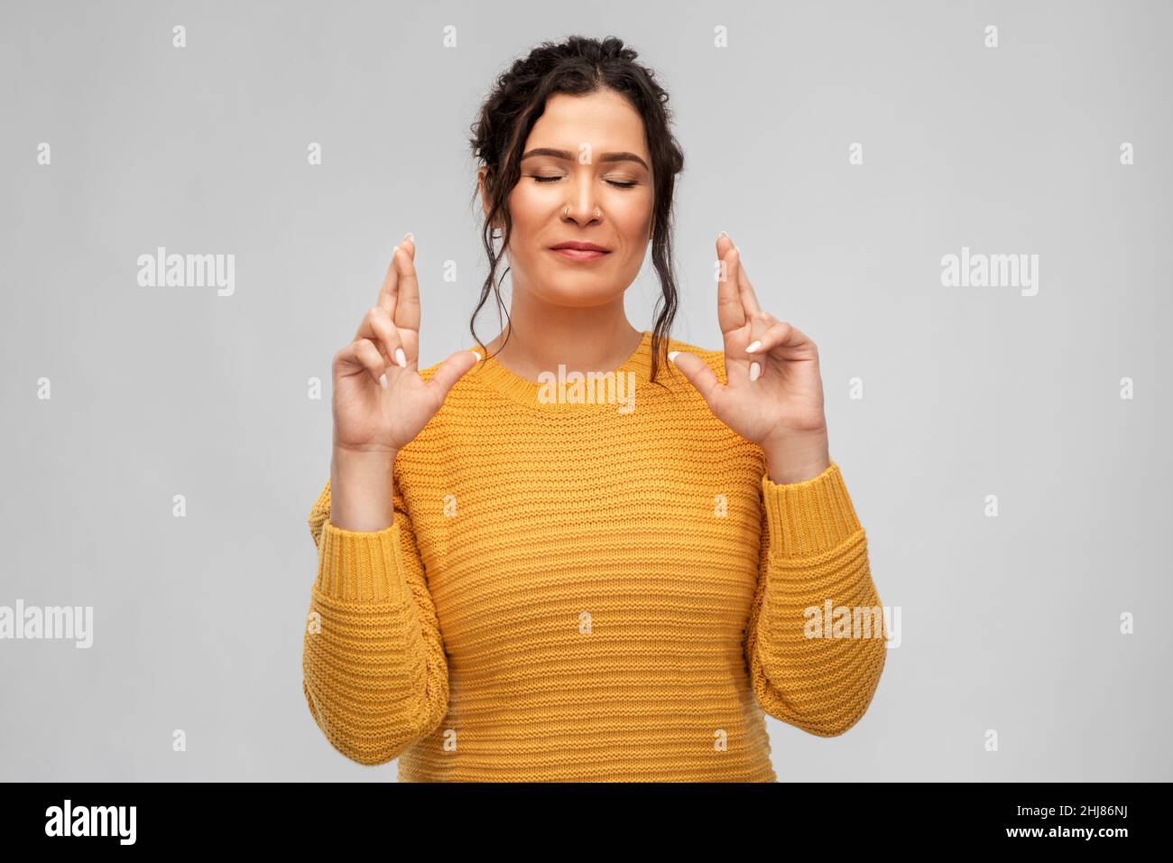woman with pierced nose holding fingers crossed Stock Photo