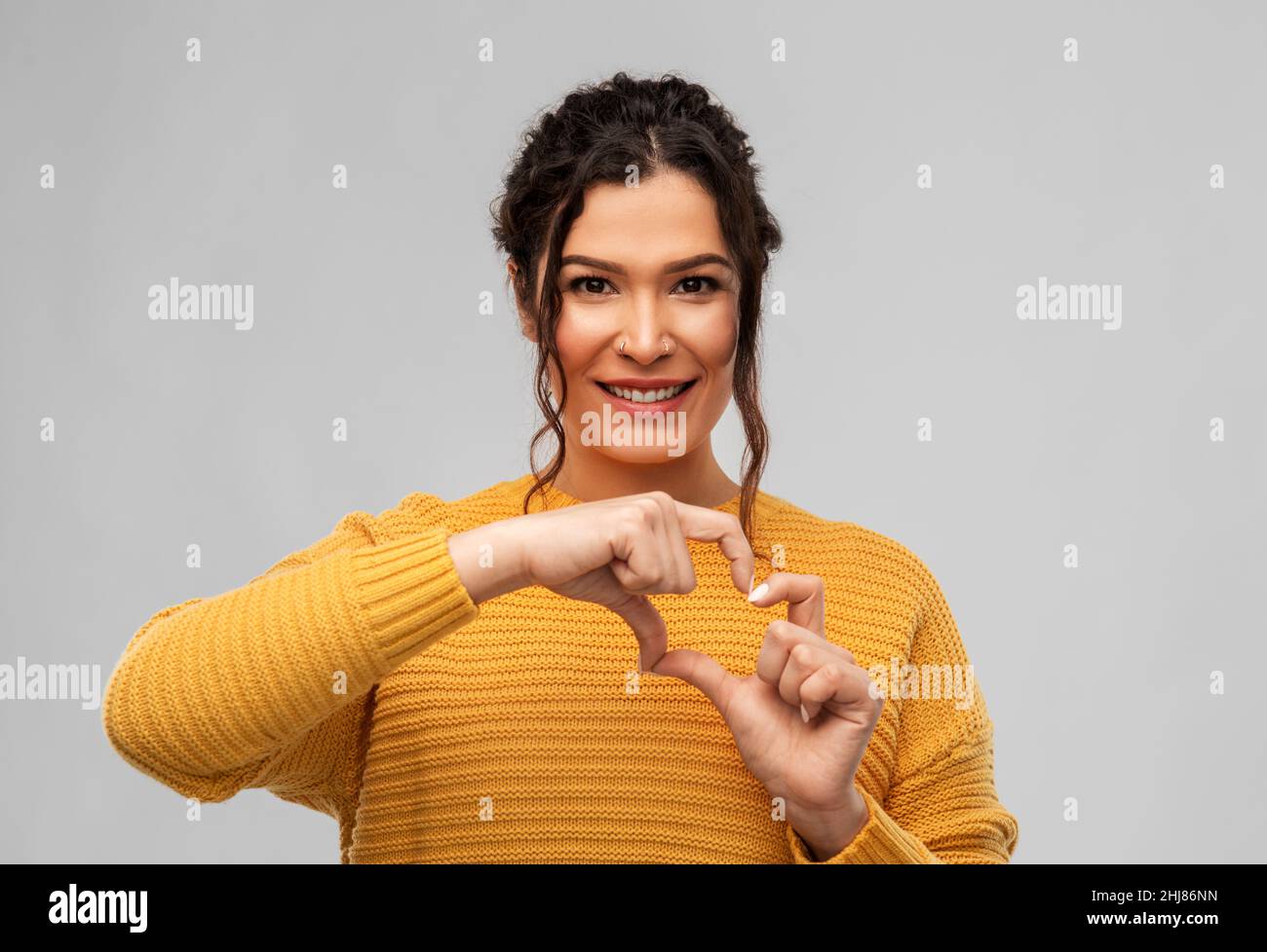 smiling young woman making hand heart gesture Stock Photo