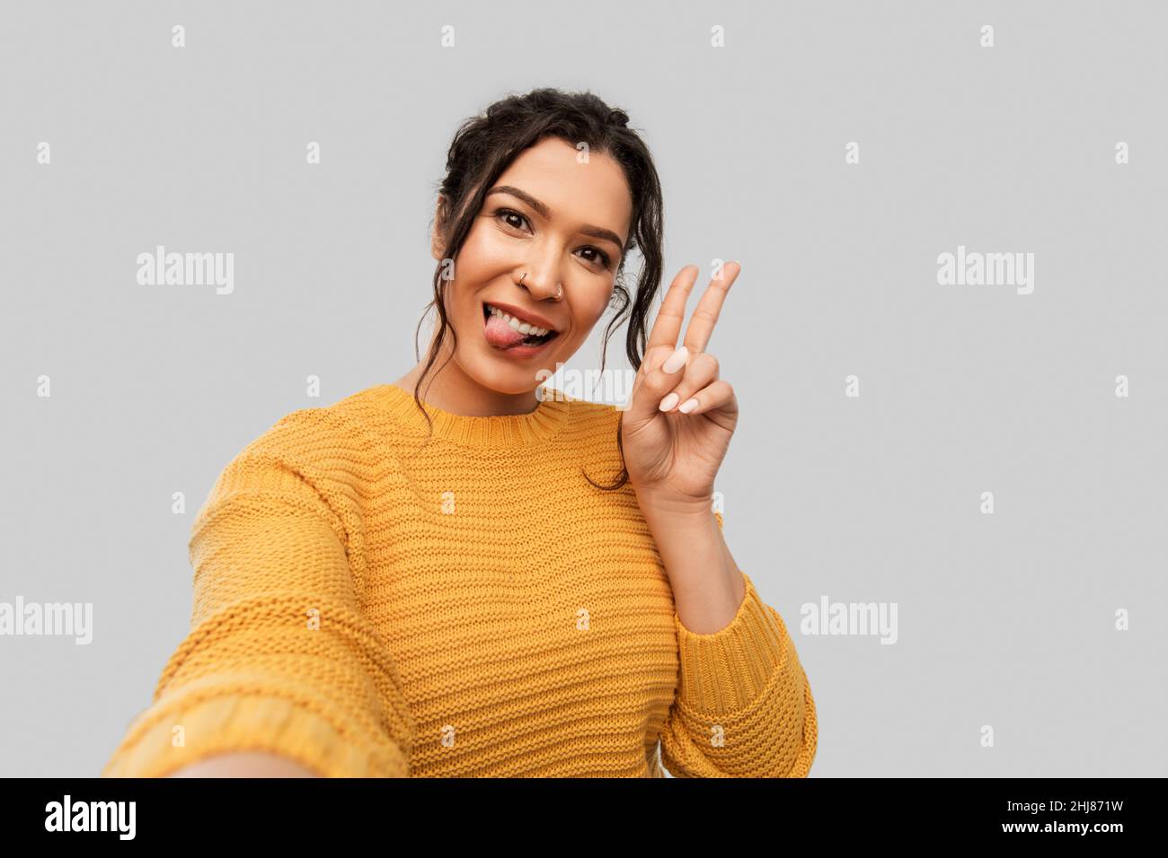 woman with pierced nose taking selfie shows peace Stock Photo
