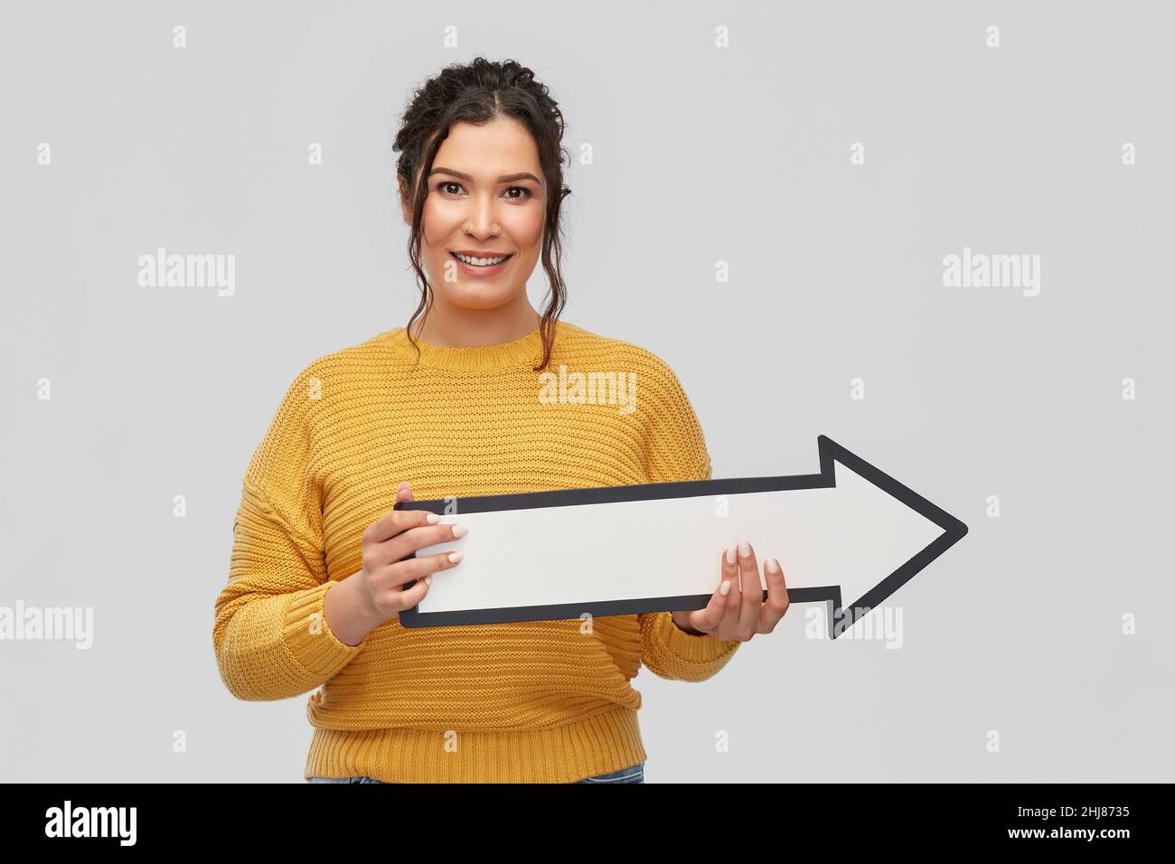 smiling young woman with big white right arrow Stock Photo
