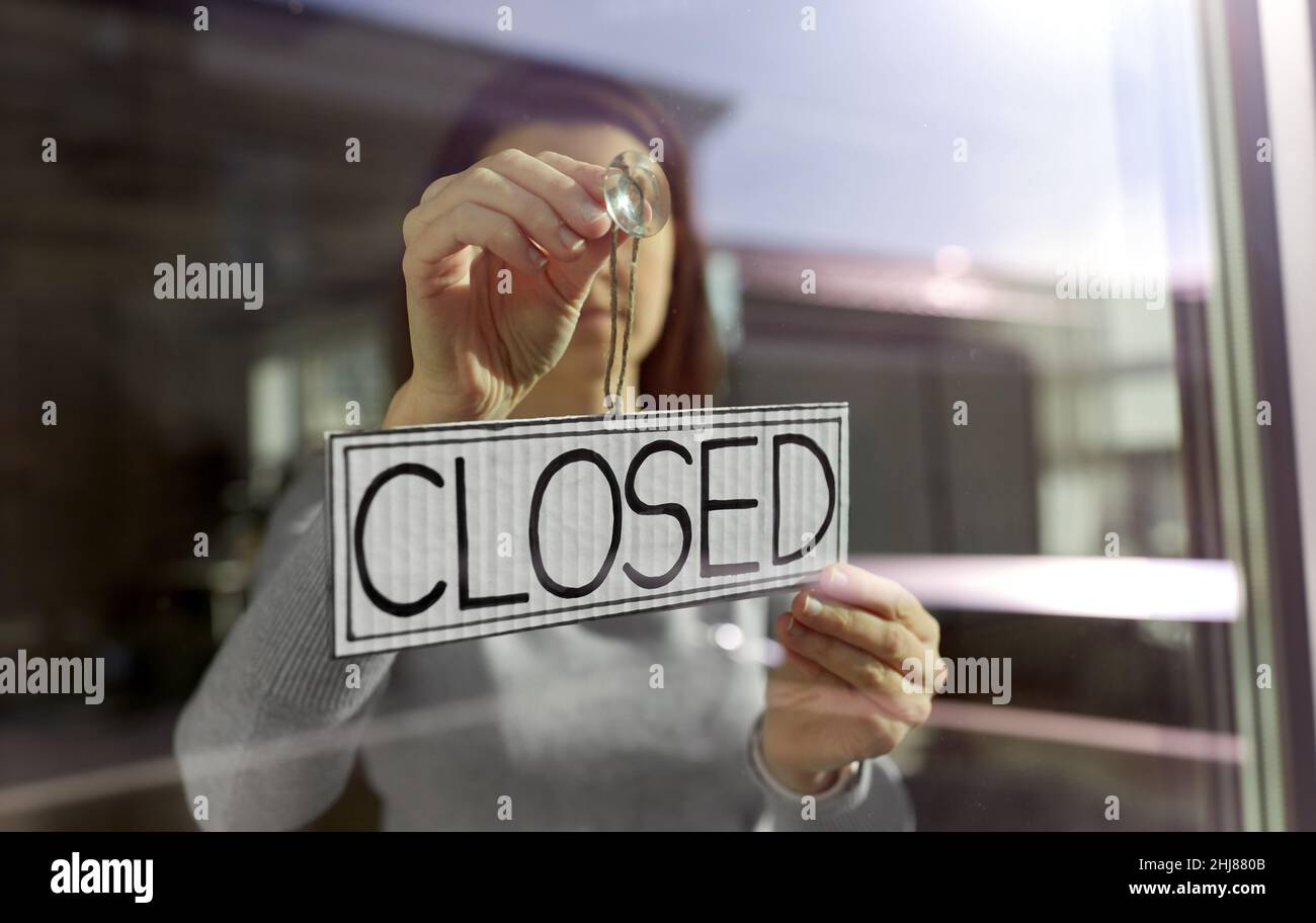 woman hanging banner with closed word on door Stock Photo
