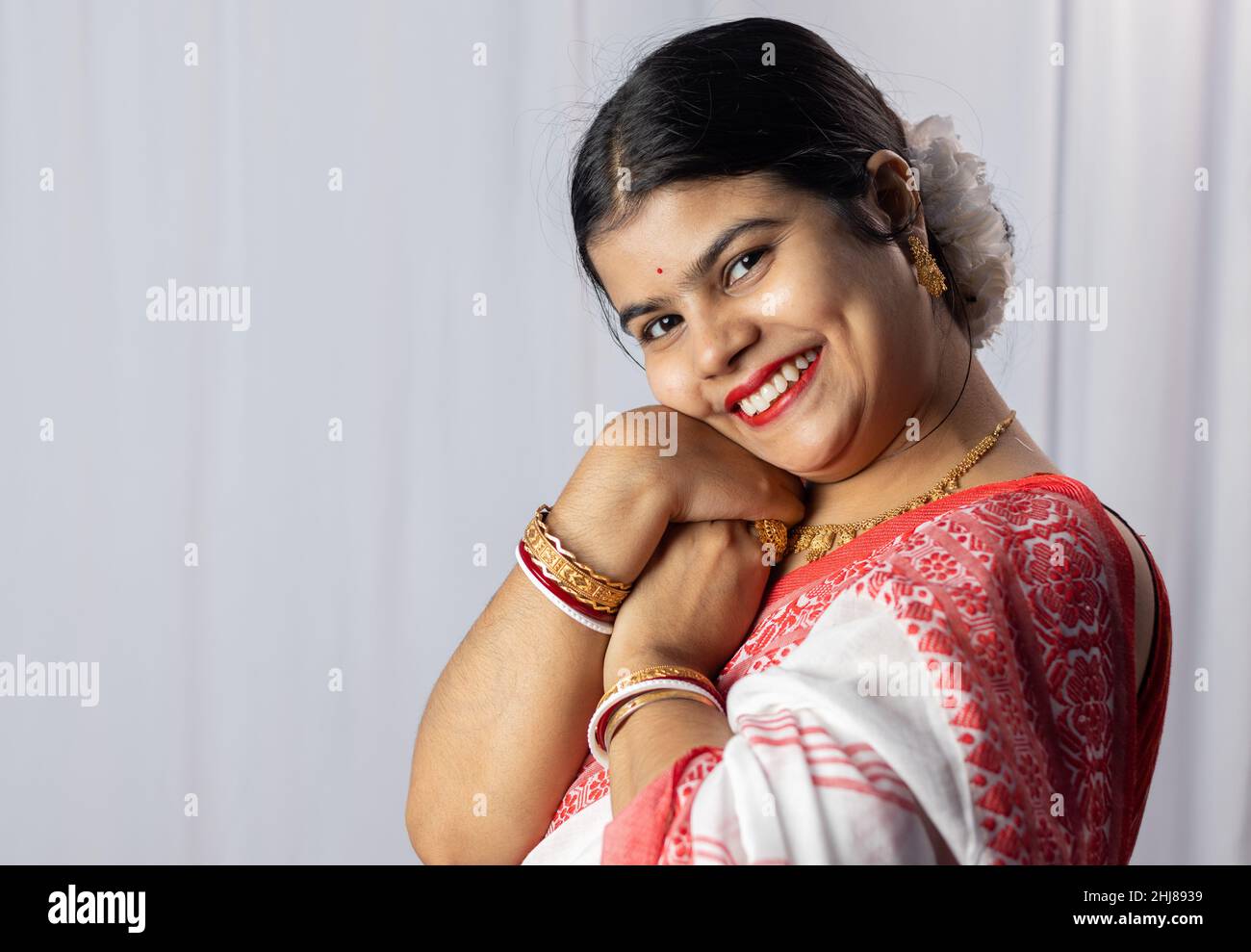 An Indian woman in red saree wearing bangles with smiling face on white background Stock Photo